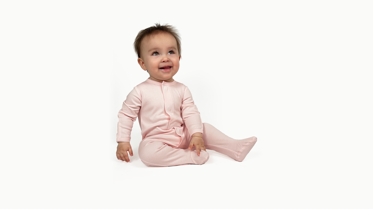 Baby in a pink Magnetic Onesie on a soft white backdrop