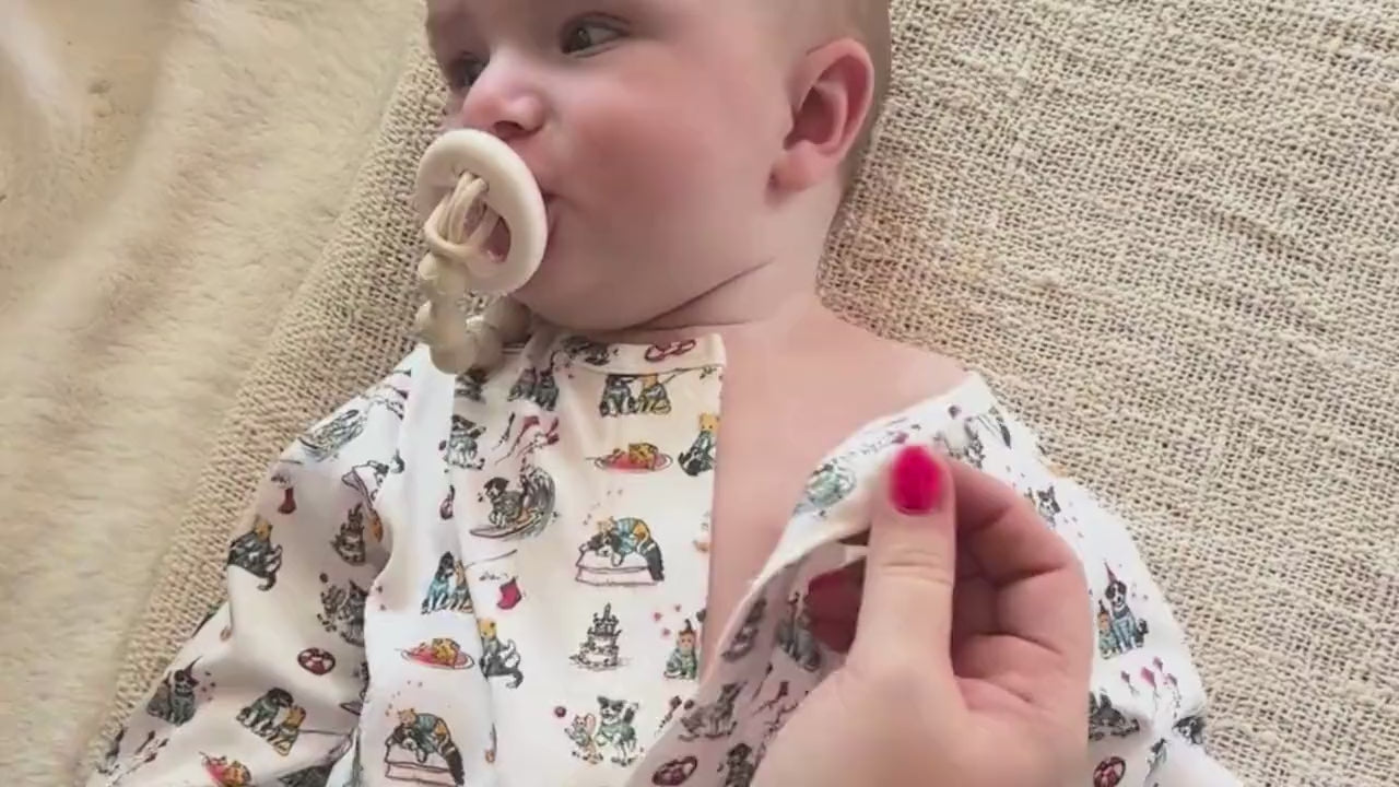 Close up of mother's hands closing a magnetic onesie.