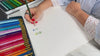 Hands drawing a flower print on paper
